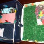 The backyard, which features both a grassy area & barbecue, was made on a shoe box lid.